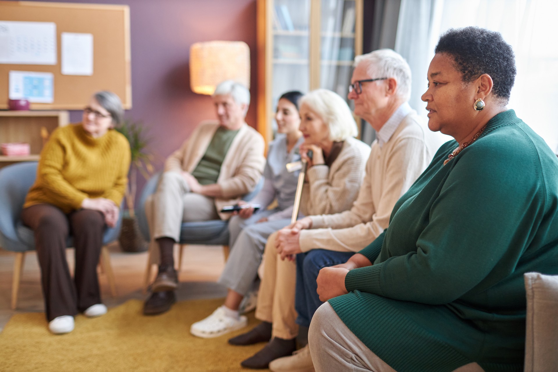 Elderly people watching TV sitting in row together in retirement home